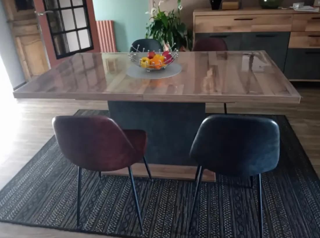 Rozťahovací stôl z viazaného dreva s košíkom na ovocie; dve kožené stoličky na koberci